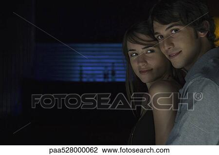 Stock Image - Woman leaning against man, glancing back over her shoulder. Fotosearch