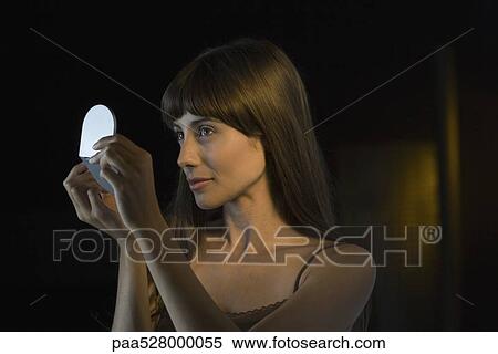 Woman looking at herself in handheld mirror View Large Photo Image Stock Photography - Woman looking at herself in handheld mirror. Fotosearch