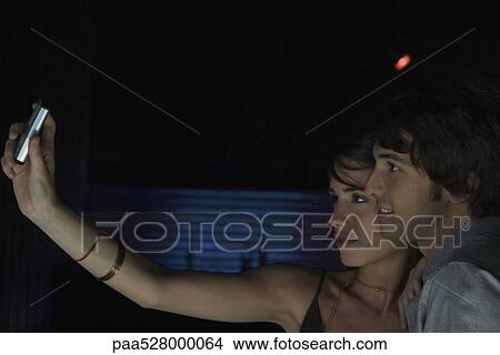 Picture - Woman using camera phone to take self portrait of her with date . Fotosearch