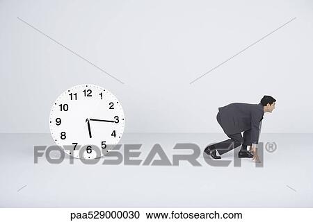 Businessman crouching, ready to run, next to clock View Large Photo Image Stock Image - Businessman crouching, ready to run, next to clock . Fotosearch