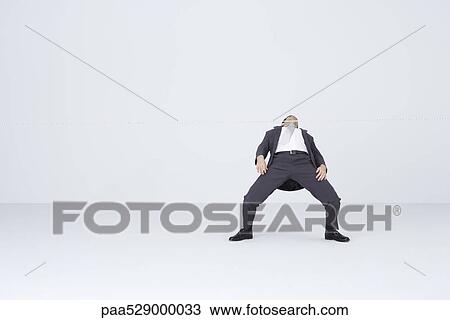 Stock Image - Businessman doing limbo, bending backwards to go under rope. Fotosearch