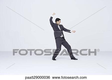 Businessman playing tug-of-war, winning View Large Photo Image Stock Photograph - Businessman playing tug-of-war, winning. Fotosearch
