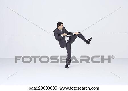 Stock Photo - Businessman pulling on rope, playing tug-of-war. Fotosearch