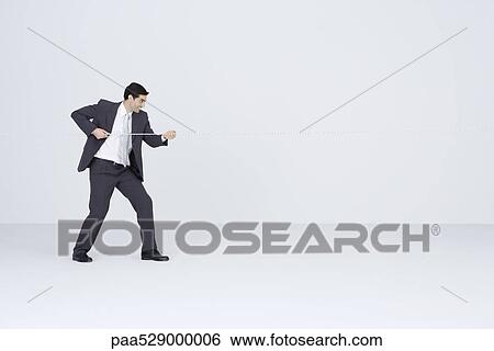 Stock Photograph - Businessman pulling rope, playing tug-of-war. Fotosearch