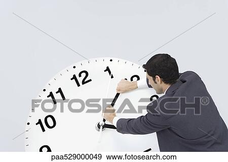 Businessman pushing back hands of clock View Large Photo Image Stock Photo - Businessman pushing back hands of clock. Fotosearch