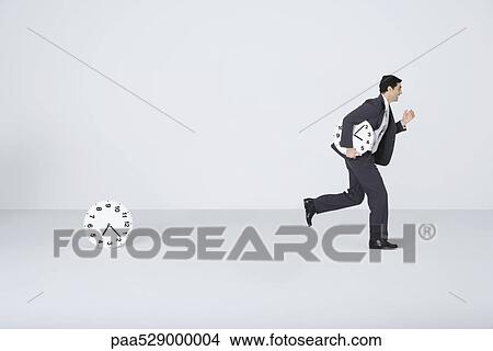Businessman running with clock, leaving second clock behind View Large Photo Image Picture - Businessman running with clock, leaving second clock behind. Fotosearch