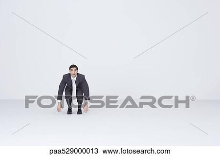 Businessman squatting, dangling arms View Large Photo Image Stock Image - Businessman squatting, dangling arms. Fotosearch