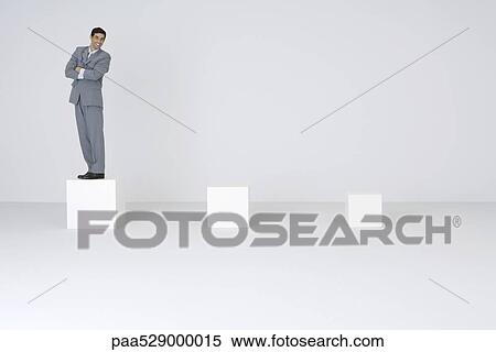 Businessman standing on biggest pedestal, smiling View Large Photo Image Stock Photography - Businessman standing on biggest pedestal, smiling. Fotosearch