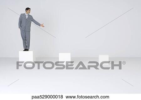 Stock Photo - Businessman standing on pedestal, presenting empty pedestals. Fotosearch