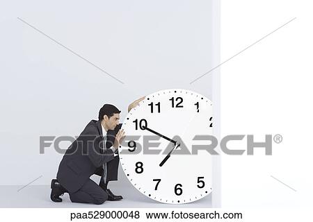 Businessman staring at oversized clock View Large Photo Image Stock Photo - Businessman staring at oversized clock. Fotosearch