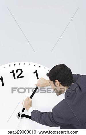 Businessman trying to turn back hands of clock View Large Photo Image Stock Image - Businessman trying to turn back hands of clock. Fotosearch