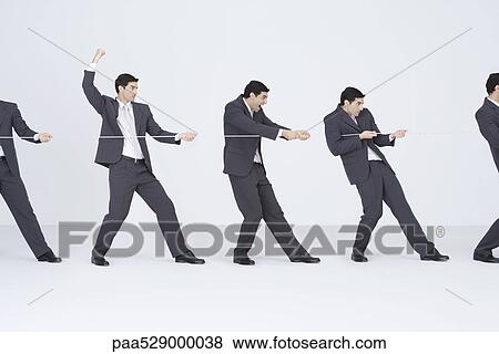 Stock Photo - Identical businessmen playing tug-of-war for the same side. Fotosearch