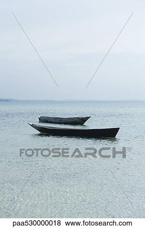 Stock Photo - Pair of empty boats floating next to each other, Zanzibar, Tanzania. Fotosearch
