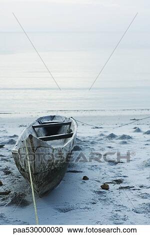 Stock Image - Tanzania, Zanzibar, dugout canoe on beach. Fotosearch