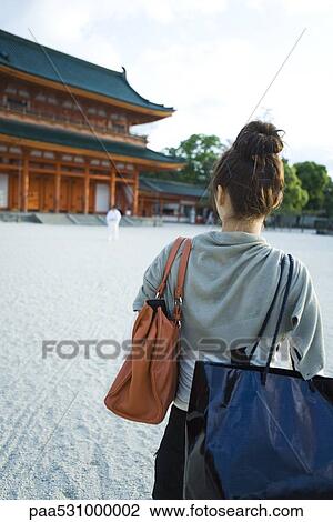 Stock Image - Female approaching Japanese temple, rear view. Fotosearch