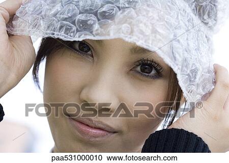 Stock Image - Female wearing hat made of bubble wrap, portrait. Fotosearch