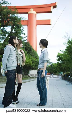 Group of friends chatting, traditional Japanese Torii gate in background View Large Photo Image Stock Image - Group of friends chatting, traditional Japanese Torii gate in background. Fotosearch
