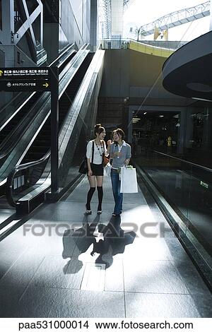 Picture - Two young women laughing in shopping center, Kyoto, Japan. Fotosearch