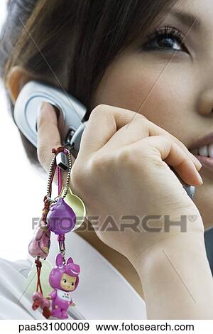 Stock Photo - Woman using cell phone decorated with charms, close-up, cropped. Fotosearch