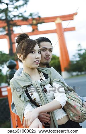 Young couple leaning against railing together, traditional Japanese Torii gate in background View Large Photo Image Stock Photography - Young couple leaning against railing together, traditional Japanese Torii gate in background. Fotosearch