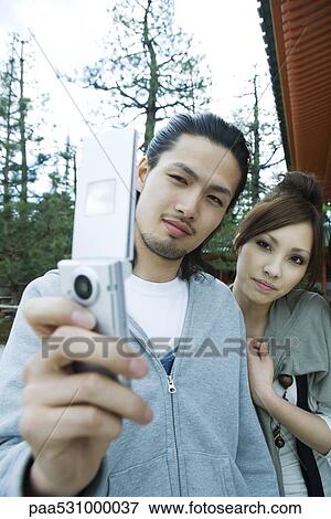 Stock Photo - Young couple photographing selves with cell phone. Fotosearch