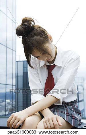 Stock Image - Young female in school uniform sitting with head down. Fotosearch