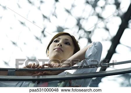 Young female leaning on railing, low angle view View Large Photo Image Stock Photo - Young female leaning on railing, low angle view. Fotosearch