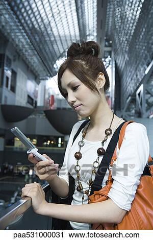 Young female text messaging on cell phone in shopping mall View Large Photo Image Stock Image - Young female text messaging on cell phone in shopping mall. Fotosearch