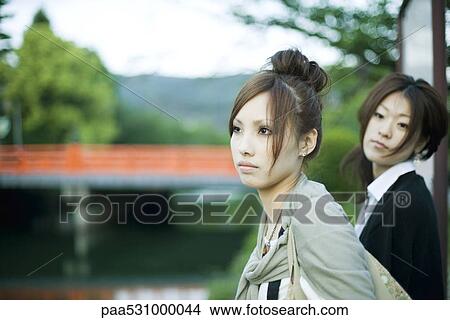 Young females outdoors, looking away, bridge in background View Large Photo Image Picture - Young females outdoors, looking away, bridge in background. Fotosearch