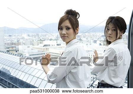 Young females standing in front of window, looking over shoulders at camera View Large Photo Image Stock Photo - Young females standing in front of window, looking over shoulders at camera. Fotosearch