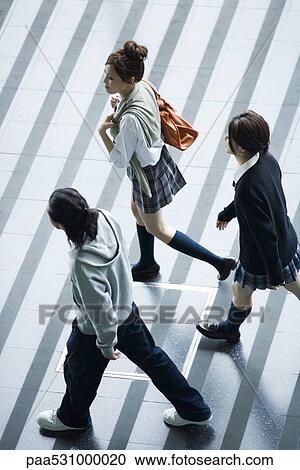 Stock Image - Young friends walking, high angle view. Fotosearch