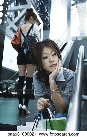 Young shopper sitting on steps, hand under chin View Large Photo Image Stock Photo - Young shopper sitting on steps, hand under chin. Fotosearch
