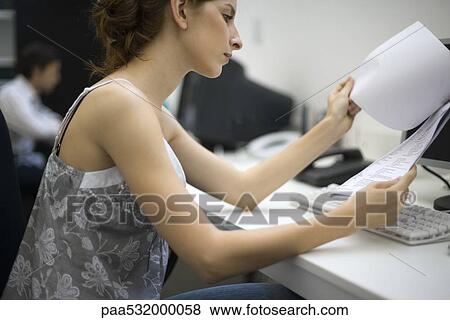 Casually dressed woman reading document at desk View Large Photo Image Stock Photo - Casually dressed woman reading document at desk. Fotosearch