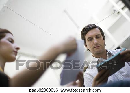 Colleagues reviewing documents, low angle view View Large Photo Image Stock Photograph - Colleagues reviewing documents, low angle view. Fotosearch