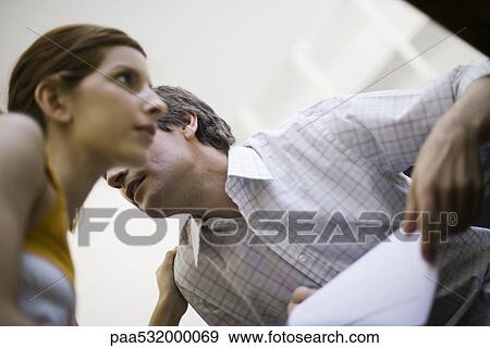 Stock Photo - Colleagues whispering, low angle view. Fotosearch