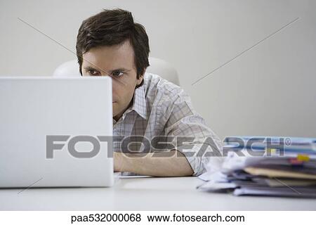 Man hunched over, working on laptop View Large Photo Image Stock Photo - Man hunched over, working on laptop. Fotosearch