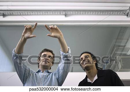 Picture - Man making gesture, explaining to colleague looking on. Fotosearch