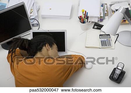 Stock Photo - Man napping at desk, overhead view. Fotosearch