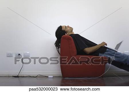 Man napping on chair, laptop balanced on lap View Large Photo Image Stock Image - Man napping on chair, laptop balanced on lap. Fotosearch
