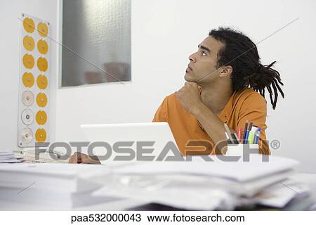 Man sitting at desk, holding chin, looking up View Large Photo Image Stock Image - Man sitting at desk, holding chin, looking up. Fotosearch