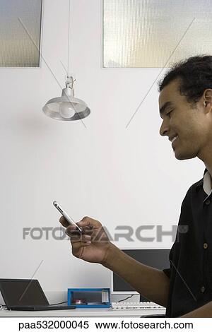 Man text messaging in office View Large Photo Image Stock Photography - Man text messaging in office. Fotosearch