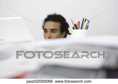 Man working at desk, obscured behind pile of documents View Large Photo Image Stock Photograph - Man working at desk, obscured behind pile of documents. Fotosearch