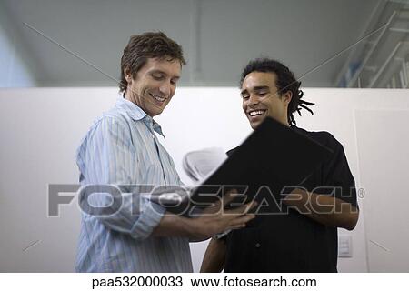 Stock Image - Men flipping through binder together. Fotosearch