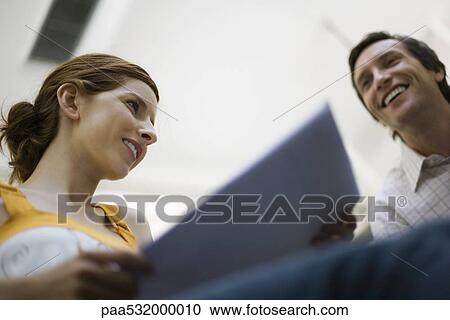 Woman holding document, man smiling nearby, low angle view View Large Photo Image Stock Image - Woman holding document, man smiling nearby, low angle view. Fotosearch