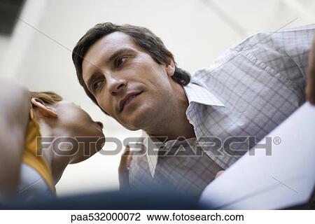 Woman whispering in man's ear, low angle view View Large Photo Image Stock Image - Woman whispering in man's ear, low angle view. Fotosearch