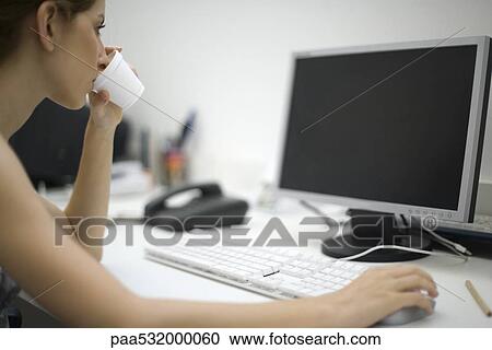 Woman working at desk, drinking from disposable cup View Large Photo Image Stock Image - Woman working at desk, drinking from disposable cup. Fotosearch