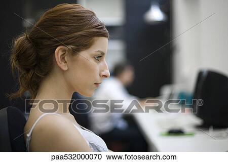 Stock Image - Woman working at desk, profile. Fotosearch