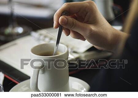 Hand stirring coffee, agenda on table in background, close-up View Large Photo Image Stock Image - Hand stirring coffee, agenda on table in background, close-up. Fotosearch
