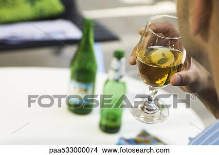 Man drinking beer from a glass, cropped, over the shoulder view View Large Photo Image Picture - Man drinking beer from a glass, cropped, over the shoulder view. Fotosearch