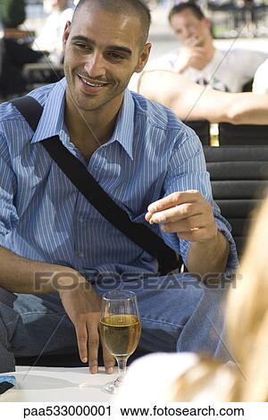 Stock Image - Man having a beer with friends at an outdoor cafe. Fotosearch